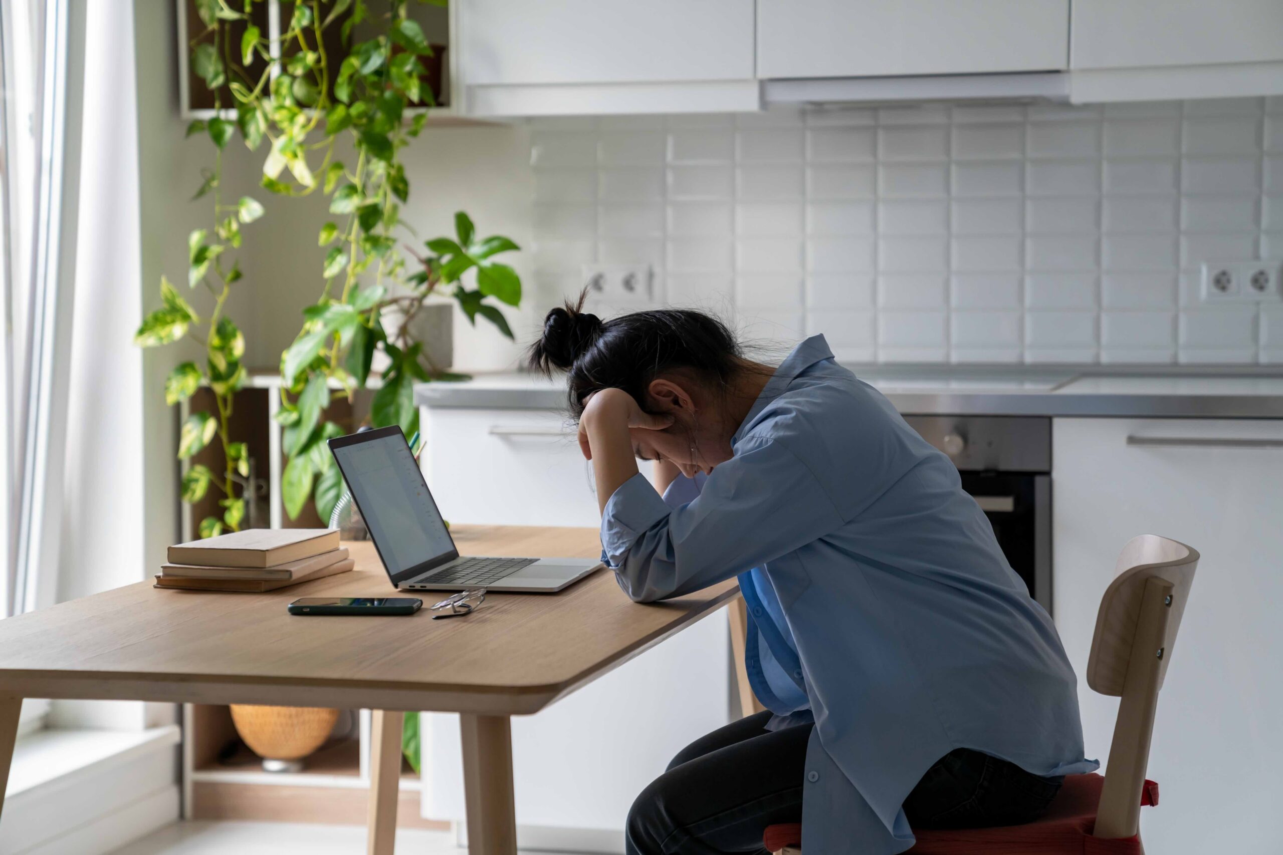 overworked woman working from home infront of laptop at her desk